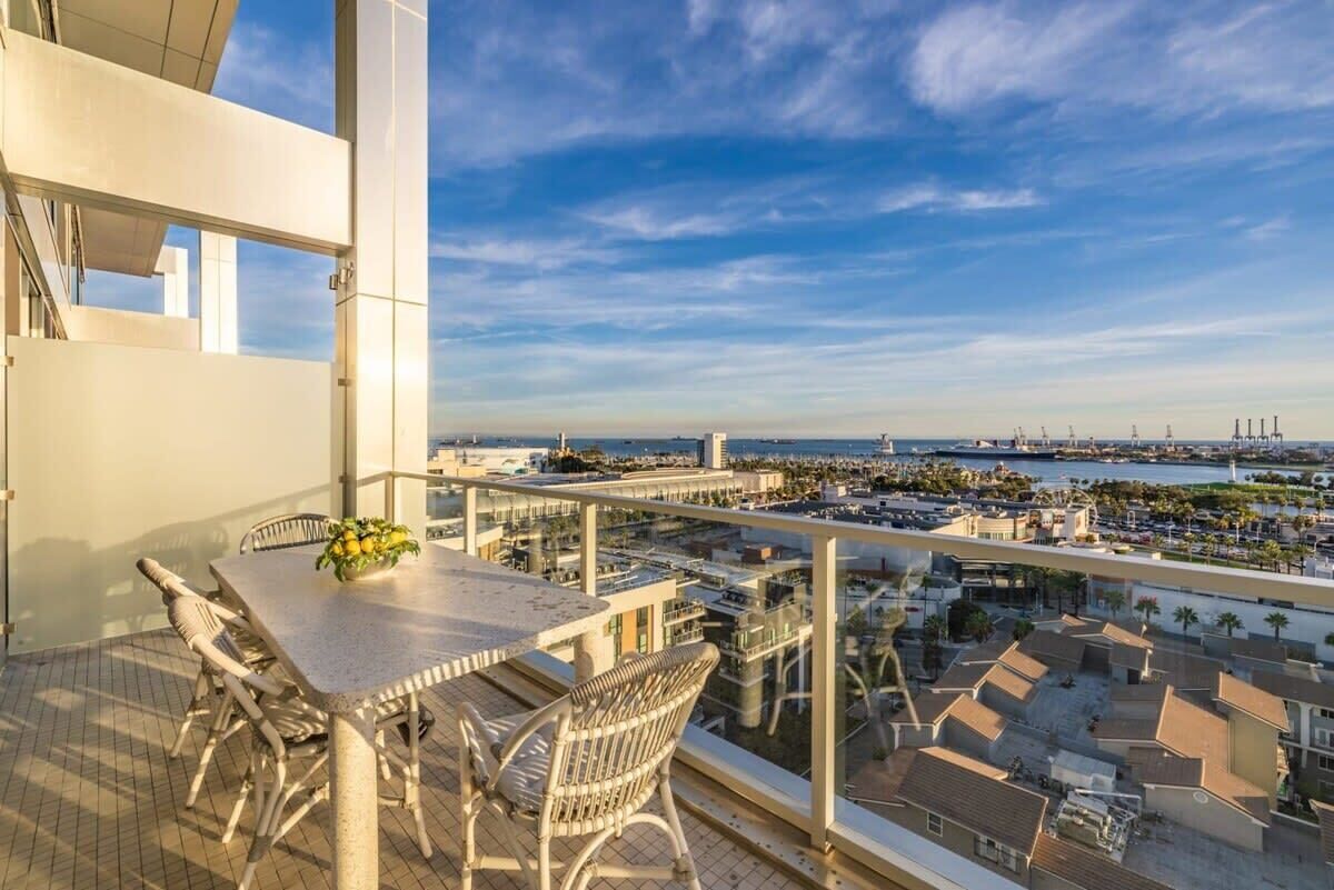A balcony with a table and chairs, overlooking a marina and cityscape.