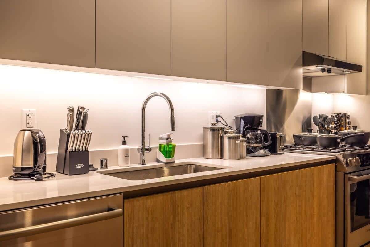 A modern kitchen with a stainless steel sink, a coffee maker, and a stove.