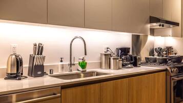 A modern kitchen with a stainless steel sink, a coffee maker, and a stove.