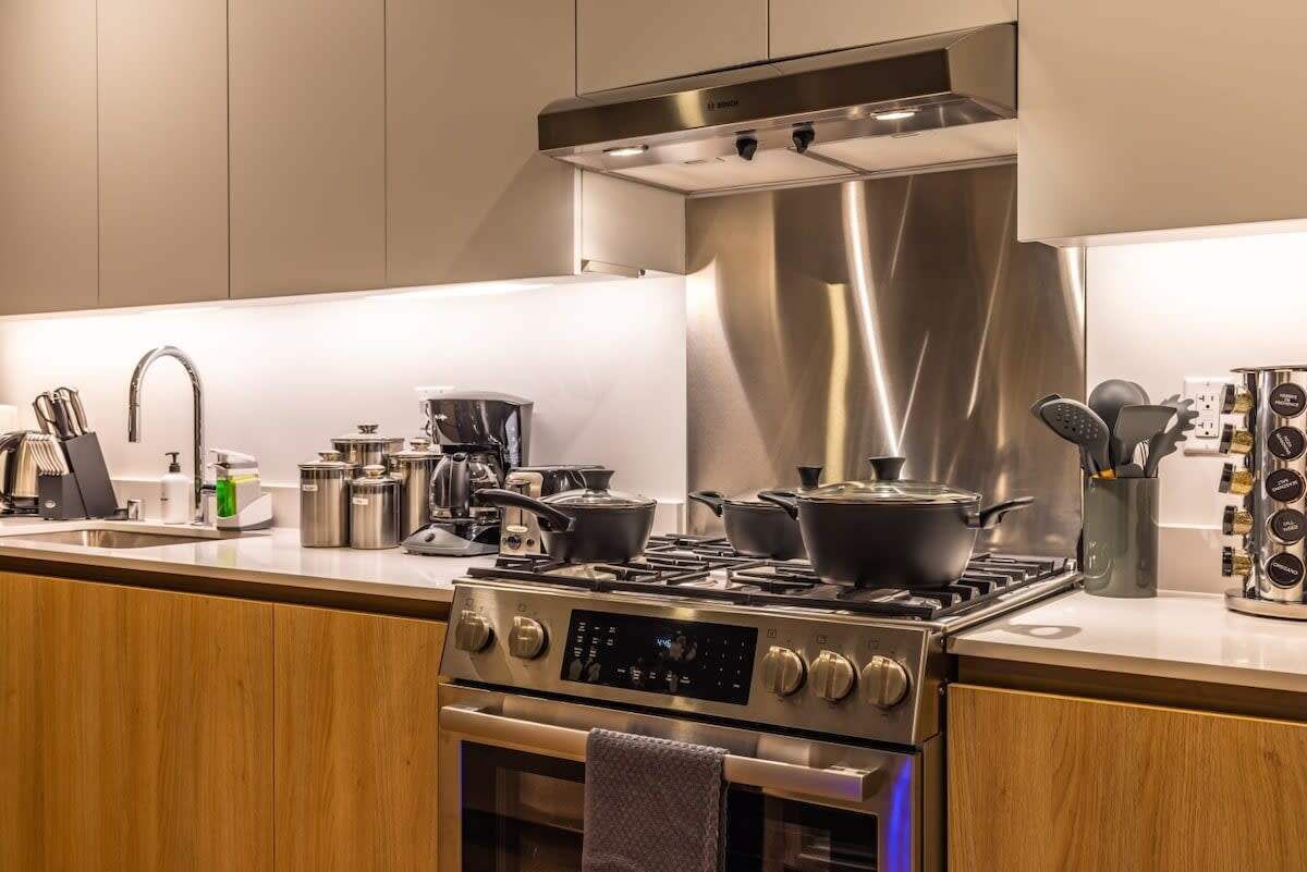 A modern kitchen with stainless steel appliances, wooden cabinets, and a built-in oven.