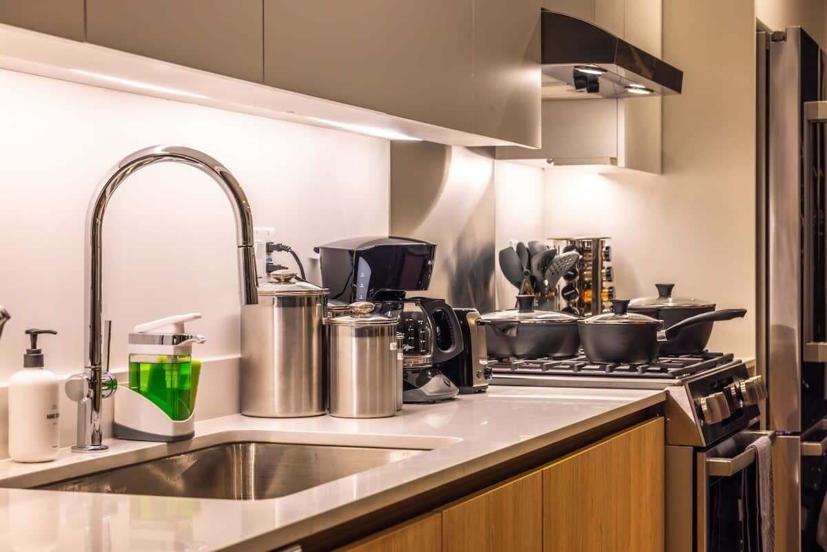 Une cuisine moderne équipée d’appareils électroménagers en acier inoxydable, d’un four encastré et d’une machine à café.