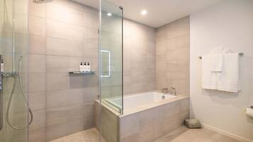 Un baño moderno con ducha de vidrio, una bañera independiente y un perchero blanco.