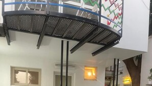 A modern outdoor patio area with a checkered floor, a round table, and chairs. There are potted plants and a small garden area with various plants. - Villa Anna Dakar (Dakar)