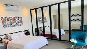 A hotel room with a bed, a sofa, a chair, a small table with a vase, and artwork on the walls. - Villa Anna Dakar (Dakar)