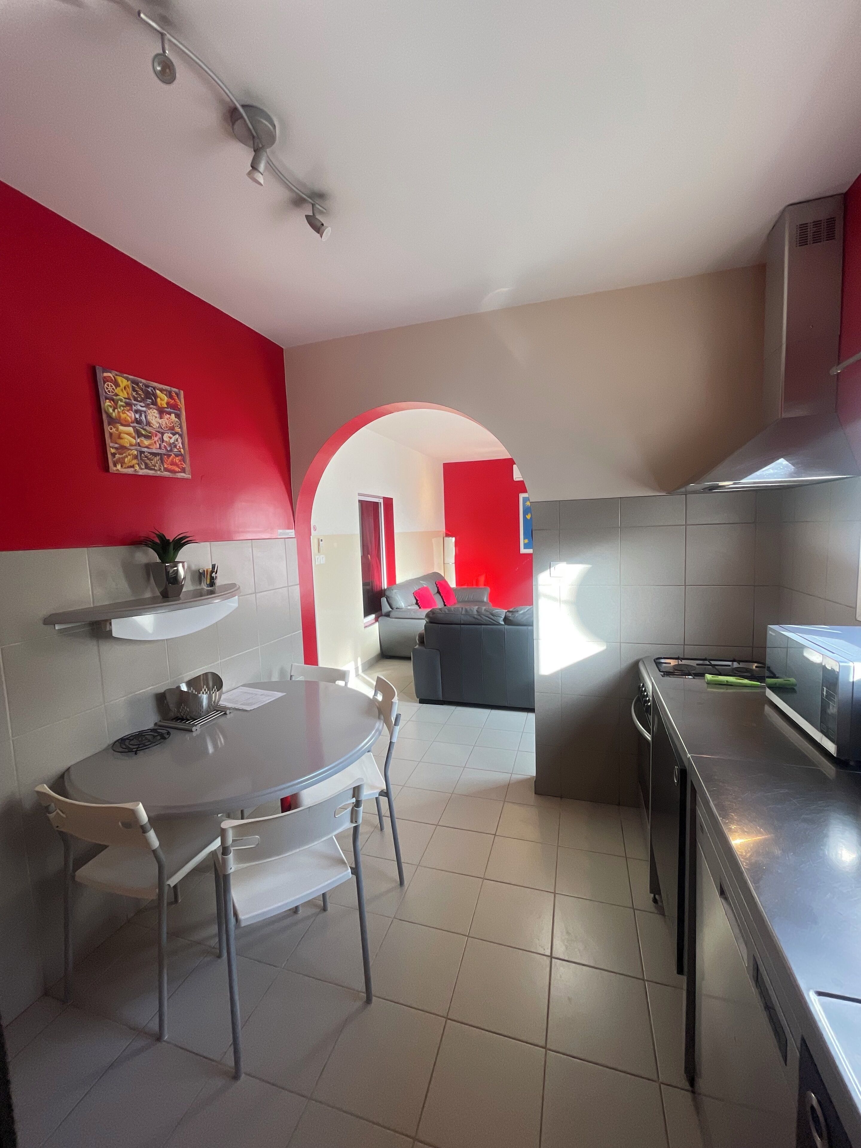 Una cocina moderna con comedor, una pared de acento roja y vista al salón.
