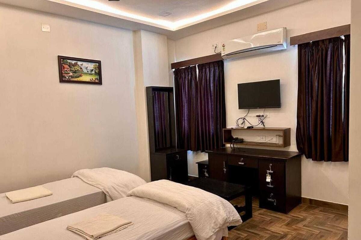 Una habitación de hotel con dos camas, un escritorio con espejo, un televisor de pantalla plana y un cuadro en la pared.