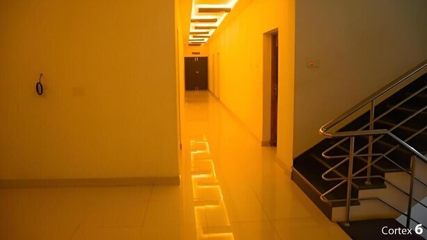 A hallway with a staircase on the right, a door at the end, and a light fixture on the ceiling.