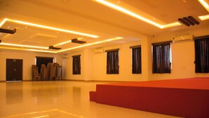 A spacious hall with a polished floor, a red seating area, and a ceiling with recessed lighting.