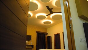 A hotel room with a ceiling fan, a bed, a TV, and a bathroom with a shower curtain.