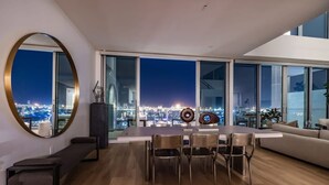 A modern dining area with a city view, large windows, and contemporary furniture. - @ Marbella Lane - Luxurious 3BR Penthouse (Long Beach)