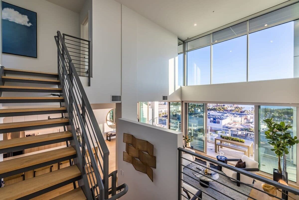 A modern interior with a staircase, a view of the city, and a dining area with a glass wall.
