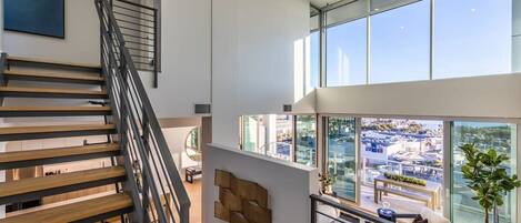 A modern interior with a staircase, a view of the city, and a dining area with a glass wall.
