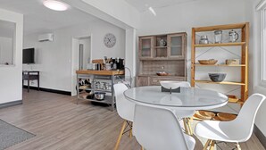 A modern kitchen with white cabinetry, a round glass table, and white chairs. - Steps to Cocoa Beach, MIL Suite & Hot Tub, Amenities Galore!! (Cocoa Beach)
