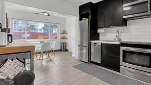 A modern kitchen with stainless steel appliances, a dining area with a table and chairs, and a view of the outside. - Steps to Cocoa Beach, MIL Suite & Hot Tub, Amenities Galore!! (Cocoa Beach)