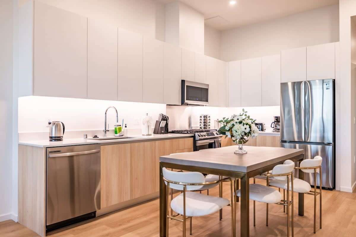 Una cocina moderna con una isla central, electrodomésticos de acero inoxidable y una zona de comedor con taburetes de bar.