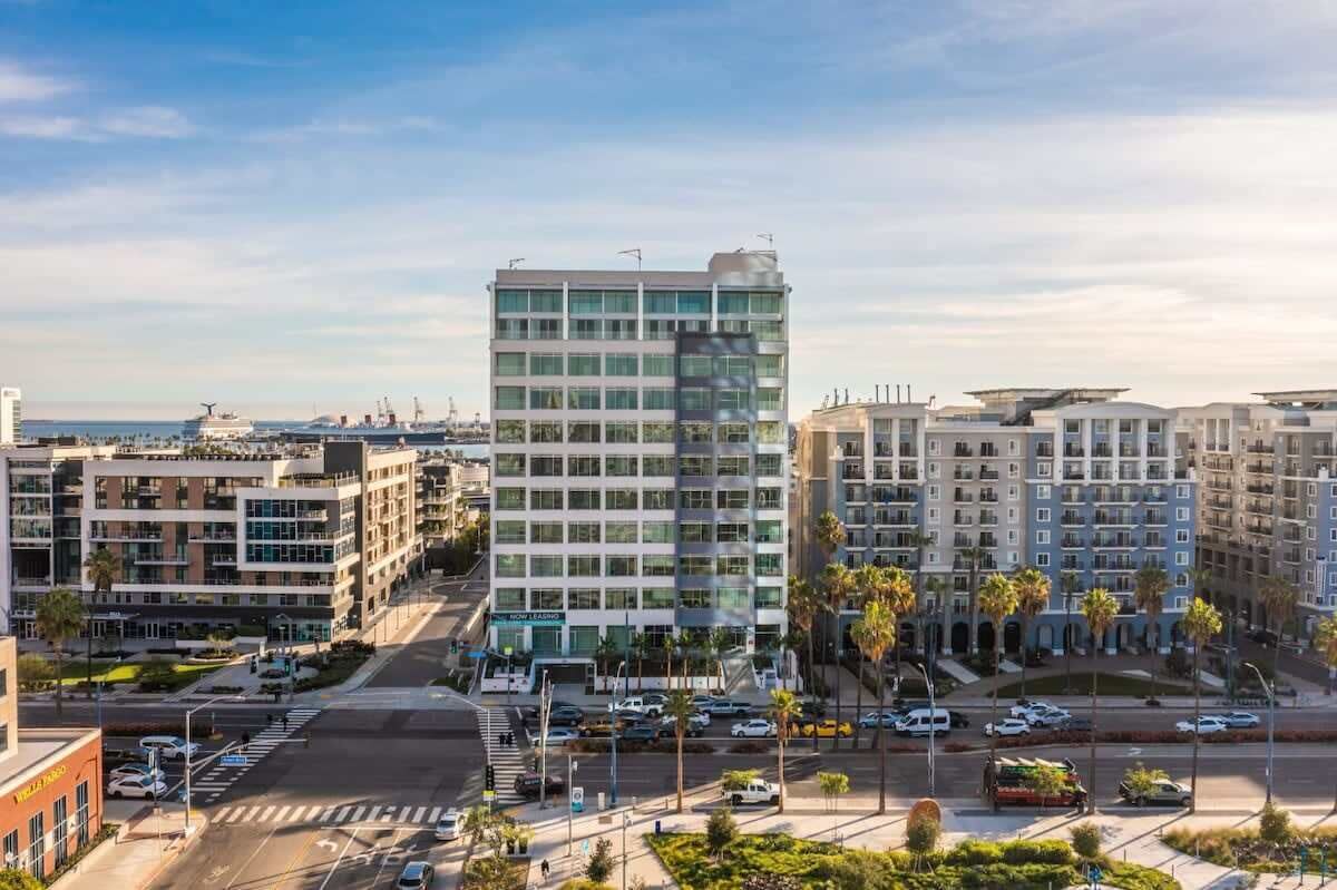 Um hotel com vários andares e design moderno, com fachada central de vidro e estacionamento em frente.