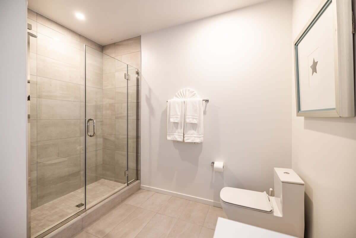A modern bathroom with a glass shower enclosure, a toilet, and a towel rack.