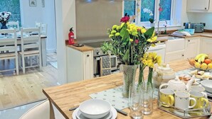 Une cuisine moderne avec un coin repas, une cuisinière, un extincteur et une fenêtre donnant sur un espace verdoyant.