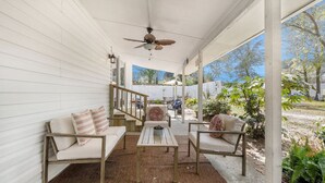 A covered porch with a ceiling fan, wooden furniture, and a view of the backyard. - Charming 3br/2ba Shem Creek Oasis! (Mount Pleasant)