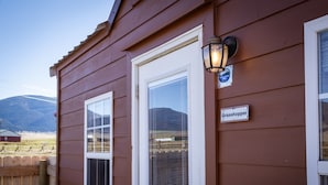 A wooden building with a white door, a window with blinds, and a sign reading "Grasshopper."