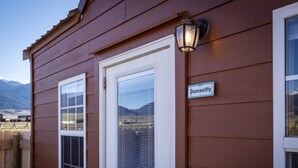 A wooden building with a white door and window, a sign reading "Pamselfly," and a wooden fence.