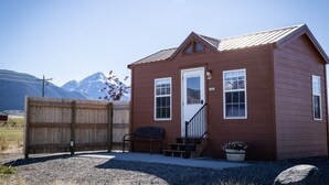 A small, single-story wooden building with a front door, windows, and a staircase leading to the entrance.