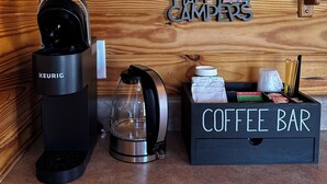 A Keurig coffee maker, a glass carafe, and a coffee bar with various items.