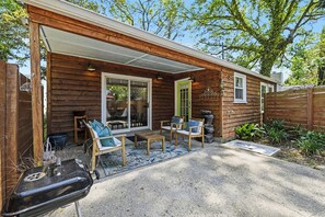 Une cabane en bois dotée d’un patio couvert, de meubles d’extérieur et d’un barbecue.