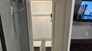 A narrow hallway leading to a closet with shelves, a door with a brass handle, and a television mounted on the wall. - HOME SWEET HOME, near USF, Bush Gardens, Adventure Island, MOSI, Downtown. (Tampa)