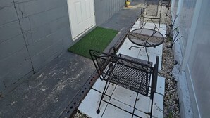 A small, enclosed outdoor area with a white door, a small window, and a metal table and chair set. - HOME SWEET HOME, near USF, Bush Gardens, Adventure Island, MOSI, Downtown. (Tampa)