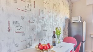 A dining area with a white table, red chairs, a bottle of wine, and a vase of flowers. - Marta - Stylish Temporary Living in Bergheim (Bergheim)