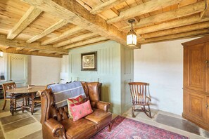 Cozy retreat with a leather sofa, wooden rocking chair, and dining table, perfect for relaxing and enjoying meals.