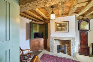 Experience a warm and inviting atmosphere with a classic wooden ceiling, cozy fireplace, and elegant grandfather clock.