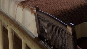 Una habitación con cama, una silla, una lámpara fijada a la pared y un ventanal.