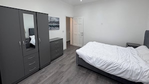 Un dormitorio con cama, armario, cómoda y puerta que da a otra habitación.