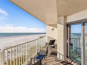 A balcony with a view of the beach, a table, and two chairs. - Newly Reno Beachfront Escape | Steps to Beach (Clearwater)
