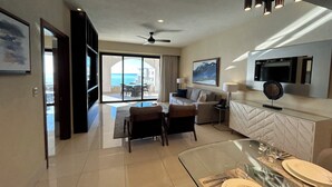 A modern hotel room with a balcony, a dining area, and a living space. - Gorgeous Oceanfront 2BR Cabo Rental – Ocean Views, Infinity Pool & Luxe Vibes (San José del Cabo)