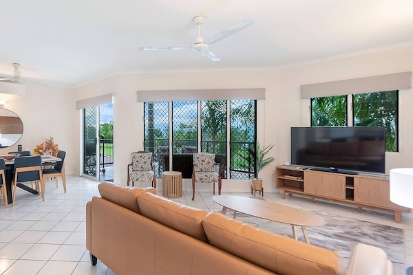 Unwind in the open-plan living area, where soft leather seating, a TV and garden-framed windows create the perfect spot to relax after a beach stroll.