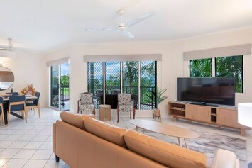 Unwind in the open-plan living area, where soft leather seating, a TV and garden-framed windows create the perfect spot to relax after a beach stroll.