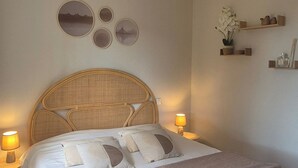 A bedroom with a bed, a ceiling fan, bedside lamps, and wall decor. - A l'ombre du clocher - Gîte with heated pool (Calenzana)