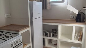A compact kitchen with a gas stove, a white refrigerator, and wooden flooring. - A l'ombre du clocher - Gîte with heated pool (Calenzana)