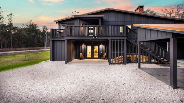 A two-story building with a balcony, a covered porch, and a staircase leading to the upper level. - Private Fairhope Waterfront Retreat, Two Complete Residences, Sleeps Up to 14 (Fairhope)