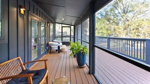 A covered outdoor area with a wooden deck, seating, and a large potted plant. - Private Fairhope Waterfront Retreat, Two Complete Residences, Sleeps Up to 14 (Fairhope)