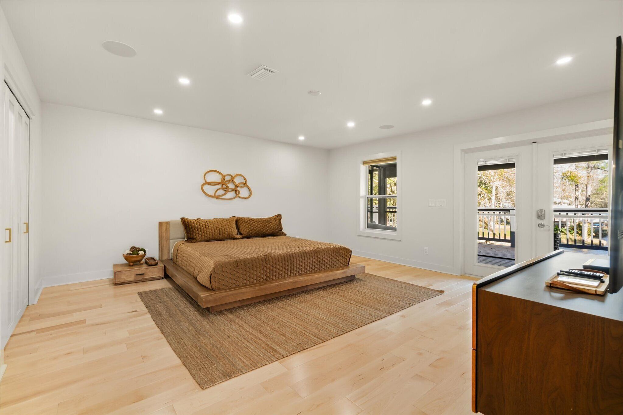 A bedroom with a bed, a desk, a window, and a door.