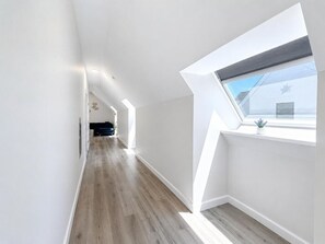 Ein modernes Interieur mit einer langen Diele, einem Oberlicht und Holzböden.