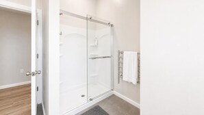 Ein modernes Badezimmer mit Duschkabine aus Glas, Handtuchhalter und Holzboden.