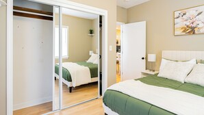 A bedroom with a bed, a nightstand, a lamp, a painting, and a closet with a sliding door.