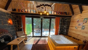 Una habitación acogedora con chimenea de piedra, una bañera grande y vistas al exterior.