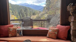 Un coin salon confortable avec vue sur une forêt et des montagnes.