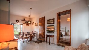 Uma sala de estar acolhedora com área de jantar, sofá e escada que leva a um quarto.